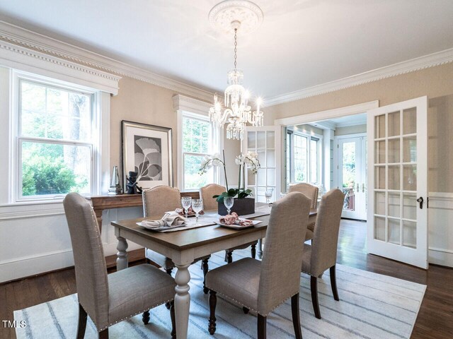 dining room with crown molding, dark wood-type flooring, an inviting chandelier, and french doors