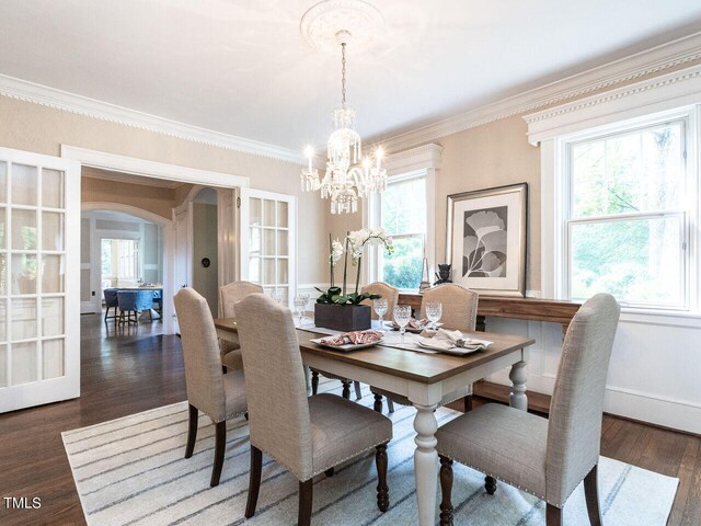 2501 Kenmore Dr, Raleigh, NC 27608 - dining room with wood finished floors, baseboards, arched walkways, ornamental molding, and a notable chandelier