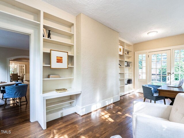 interior space with built in shelves, dark hardwood / wood-style flooring, a textured ceiling, and french doors