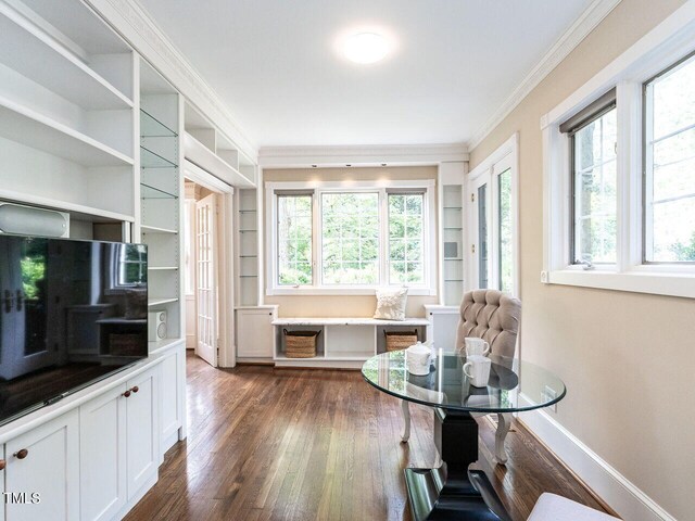 sitting room with dark hardwood / wood-style flooring, crown molding, a wealth of natural light, and built in shelves