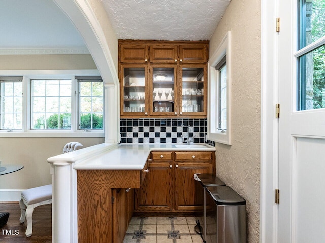 bar with plenty of natural light, sink, a textured ceiling, and decorative backsplash