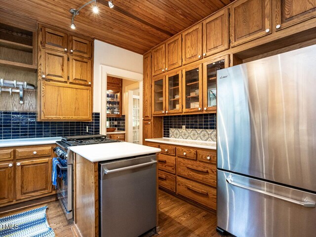 kitchen featuring appliances with stainless steel finishes, wood-type flooring, decorative backsplash, a center island, and wooden ceiling