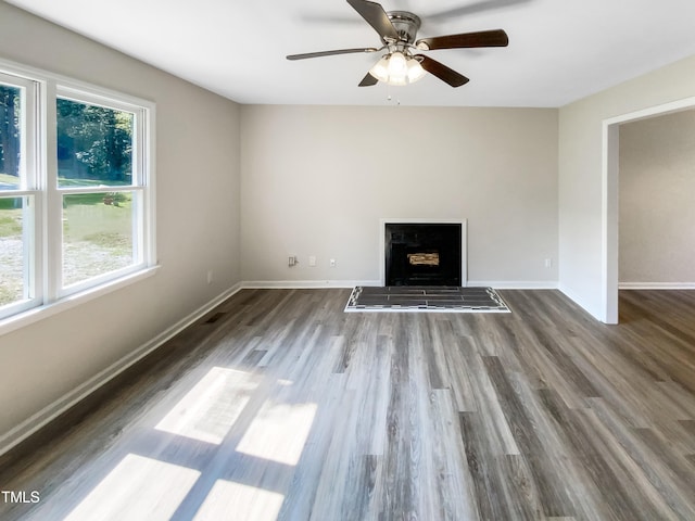 unfurnished living room featuring ceiling fan, a wealth of natural light, and hardwood / wood-style flooring