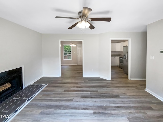 unfurnished living room featuring dark wood-type flooring and ceiling fan