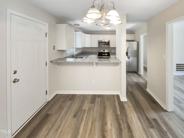 kitchen with white cabinets, light stone counters, stainless steel appliances, dark wood-type flooring, and pendant lighting