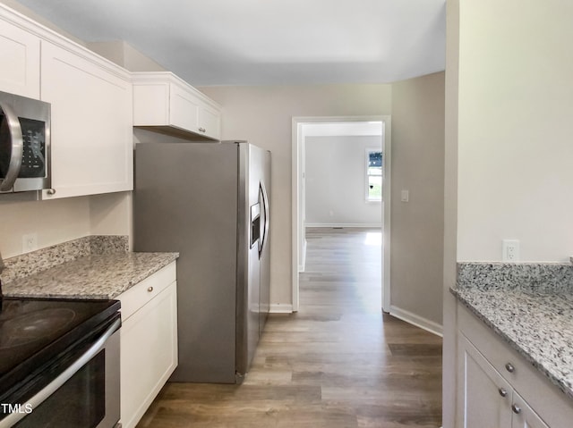 kitchen featuring hardwood / wood-style flooring, light stone countertops, appliances with stainless steel finishes, and white cabinetry