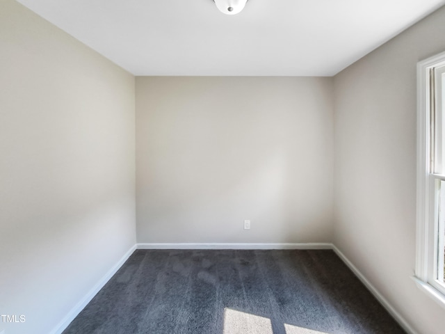 spare room featuring dark carpet