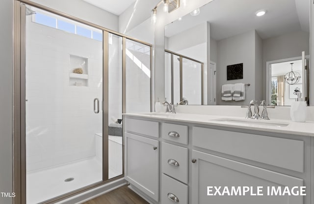 bathroom featuring wood-type flooring, an enclosed shower, and vanity