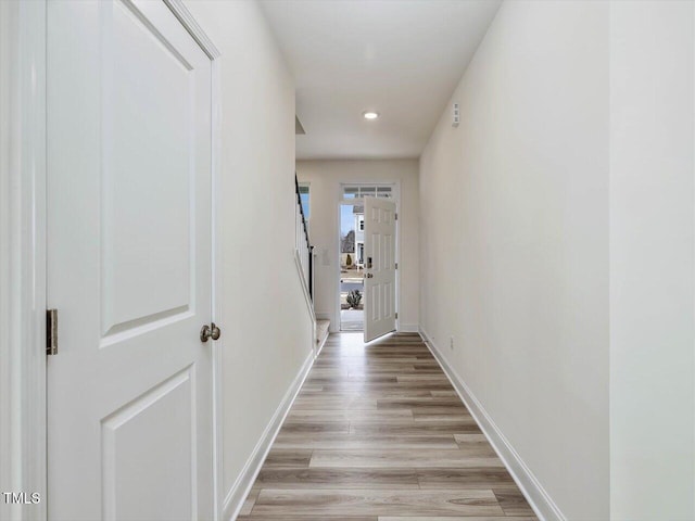 hallway with recessed lighting, light wood-style floors, and baseboards