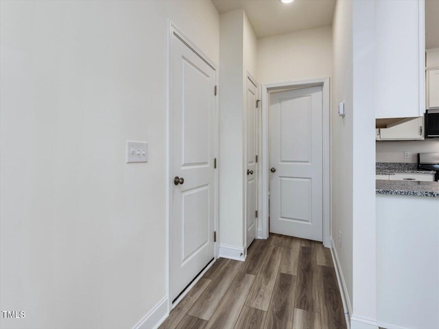 hallway featuring baseboards and wood finished floors