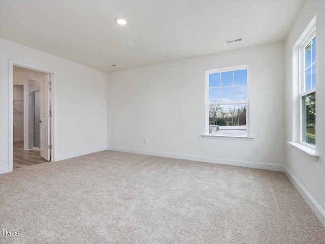 empty room with baseboards, carpet, visible vents, and a healthy amount of sunlight