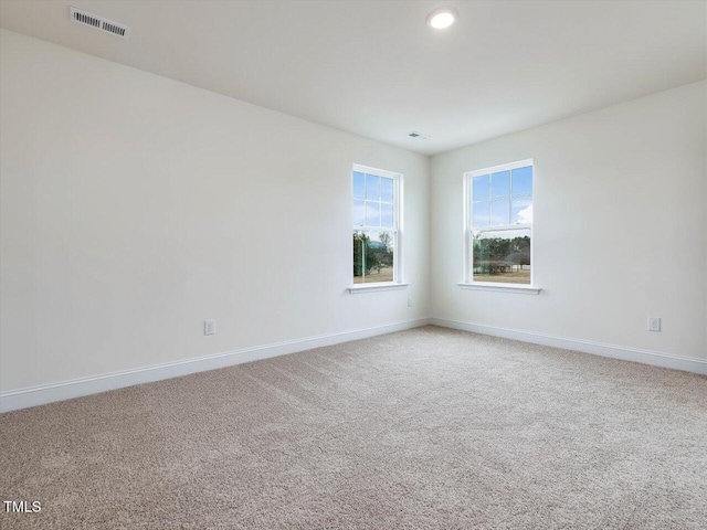 unfurnished room with visible vents, light colored carpet, and baseboards