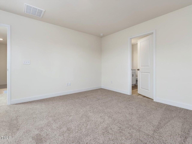 empty room featuring light colored carpet, visible vents, and baseboards