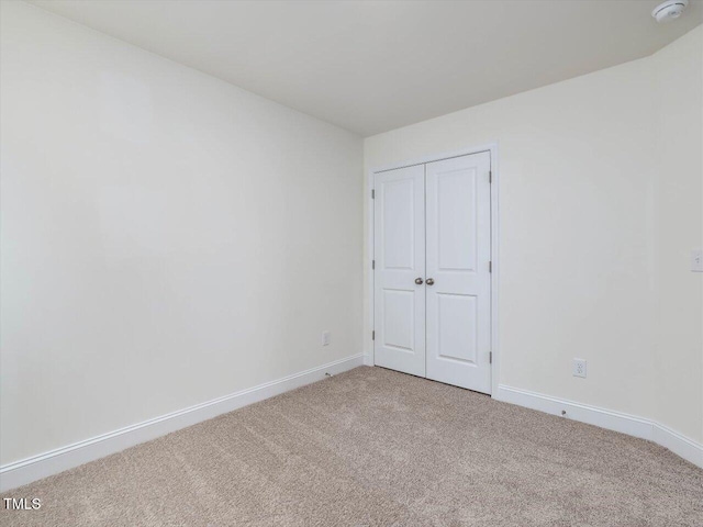 unfurnished room featuring baseboards and light carpet