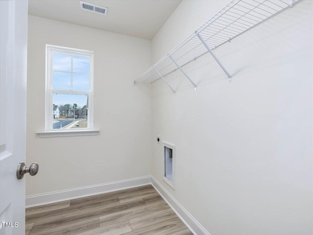 laundry area with light wood-type flooring, visible vents, baseboards, hookup for an electric dryer, and laundry area