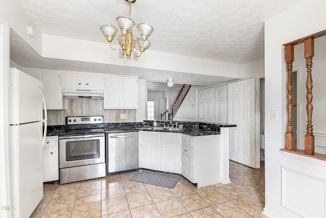 kitchen featuring a textured ceiling, stainless steel appliances, kitchen peninsula, an inviting chandelier, and white cabinets