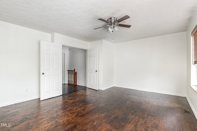 empty room with ceiling fan, dark hardwood / wood-style flooring, and a textured ceiling