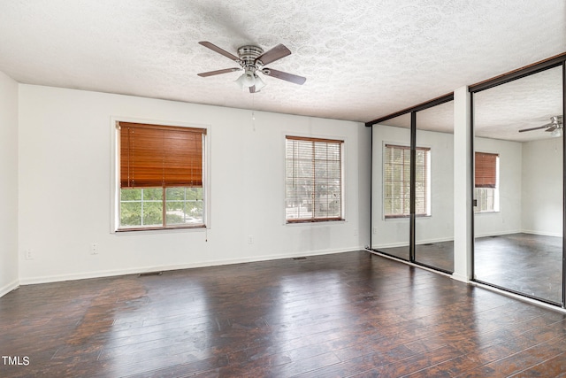 unfurnished bedroom featuring dark hardwood / wood-style flooring, two closets, ceiling fan, and a textured ceiling