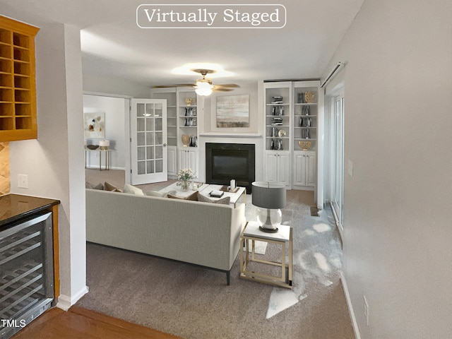 carpeted living room featuring built in shelves, ceiling fan, and wine cooler