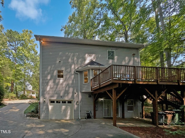 back of house featuring a deck, concrete driveway, and a garage