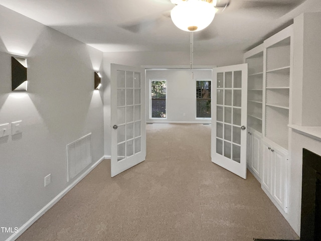 interior space with visible vents, baseboards, light carpet, french doors, and a fireplace