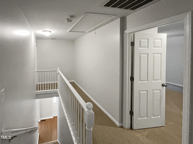 corridor with an upstairs landing, attic access, and baseboards