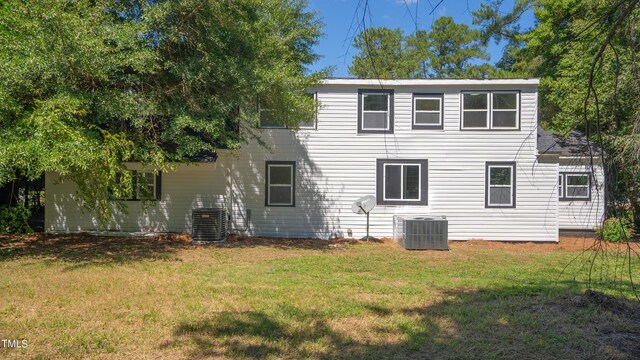 rear view of property with central air condition unit and a yard