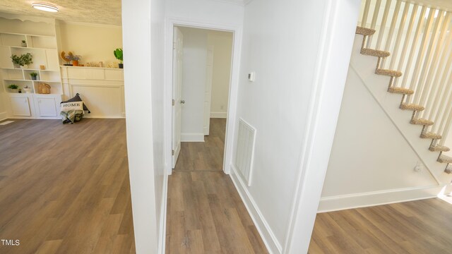 corridor with a textured ceiling and hardwood / wood-style floors