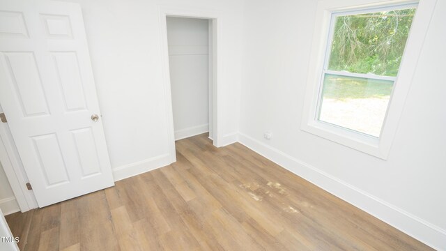 unfurnished bedroom featuring light wood-type flooring and a closet