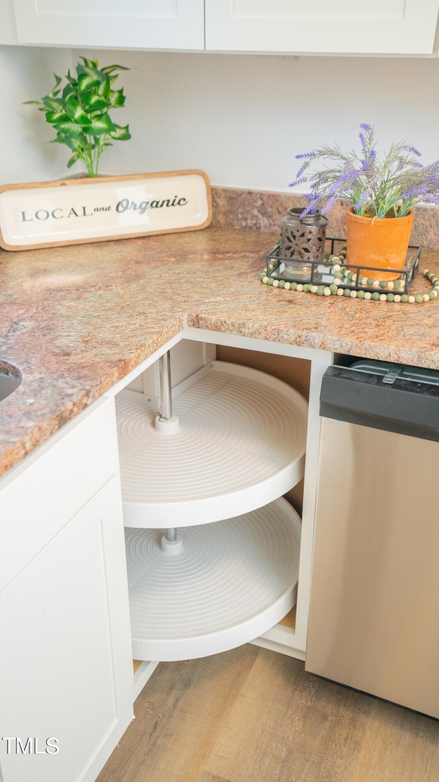 room details featuring light wood-type flooring, light stone counters, and white cabinets