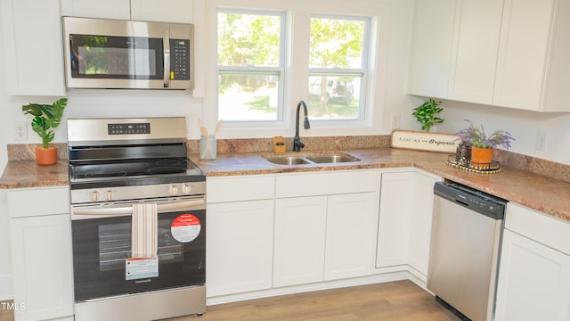 kitchen with white cabinets, light hardwood / wood-style floors, appliances with stainless steel finishes, and sink