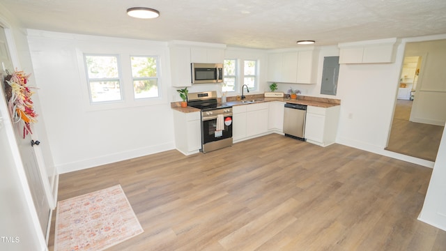 kitchen with light hardwood / wood-style flooring, white cabinetry, appliances with stainless steel finishes, and sink