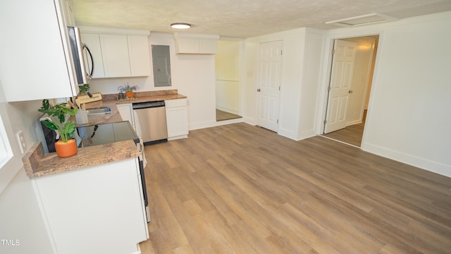 kitchen with electric panel, a textured ceiling, white cabinetry, stainless steel appliances, and light hardwood / wood-style floors