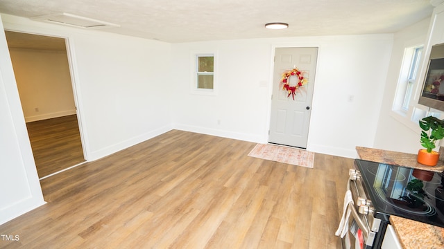 entrance foyer featuring a textured ceiling, light hardwood / wood-style flooring, and a healthy amount of sunlight