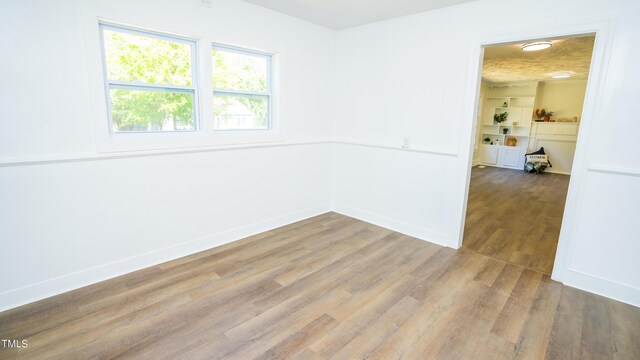 unfurnished room with a textured ceiling and hardwood / wood-style floors