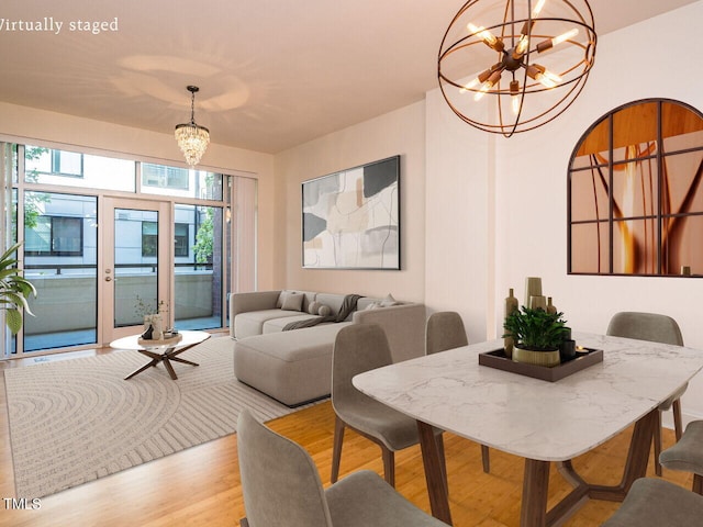 dining space featuring french doors, a notable chandelier, and light wood-type flooring