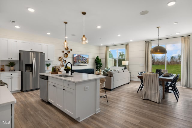 kitchen featuring white cabinets, stainless steel appliances, a center island with sink, and sink