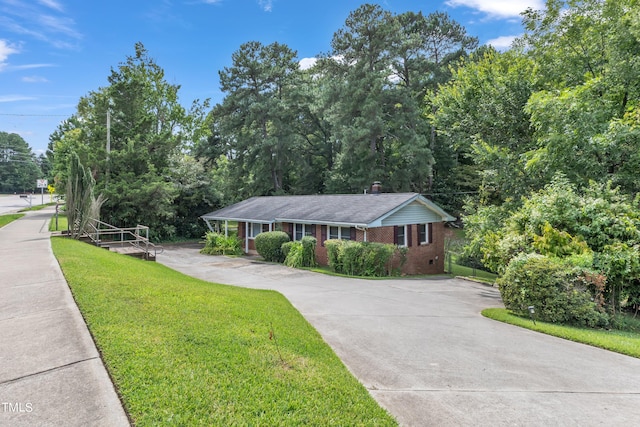 ranch-style house with brick siding, a front yard, a chimney, crawl space, and driveway