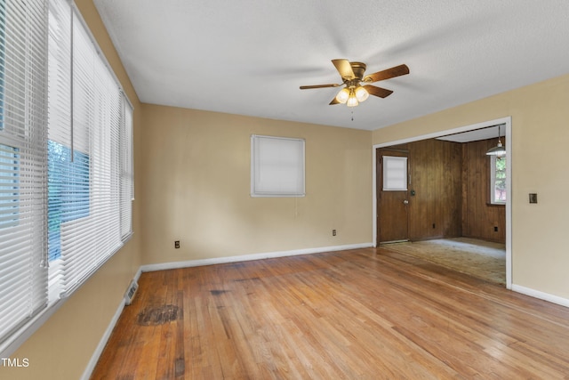 spare room with visible vents, a ceiling fan, a textured ceiling, wood finished floors, and baseboards