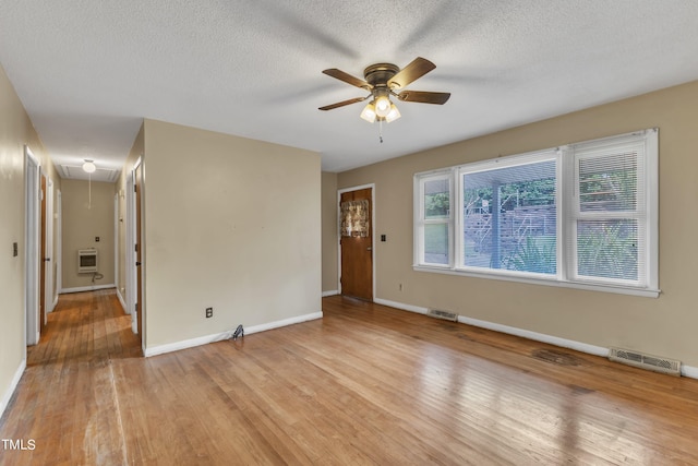 unfurnished room with attic access, heating unit, visible vents, and light wood-type flooring