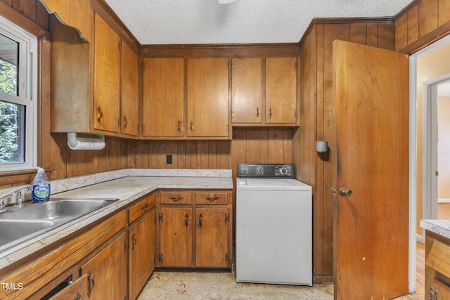 laundry area featuring a textured ceiling, washer / clothes dryer, cabinet space, and a sink