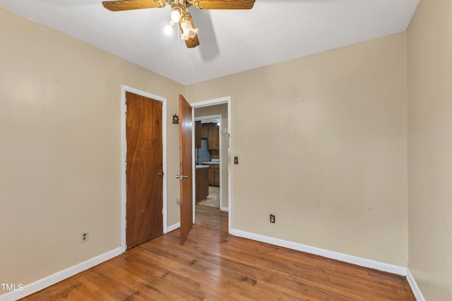 spare room with wood finished floors, baseboards, and ceiling fan