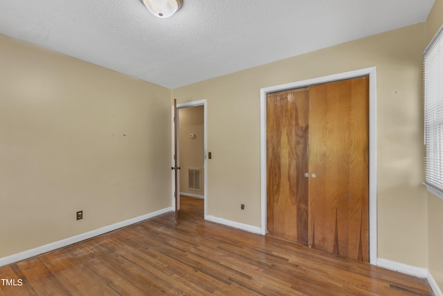 unfurnished bedroom with visible vents, wood finished floors, baseboards, and a textured ceiling