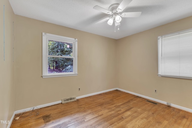 unfurnished room with light wood finished floors, visible vents, a textured ceiling, and baseboards