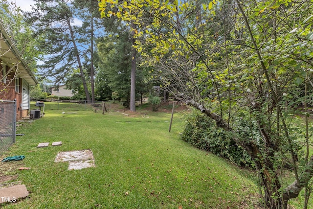 view of yard with central AC and fence