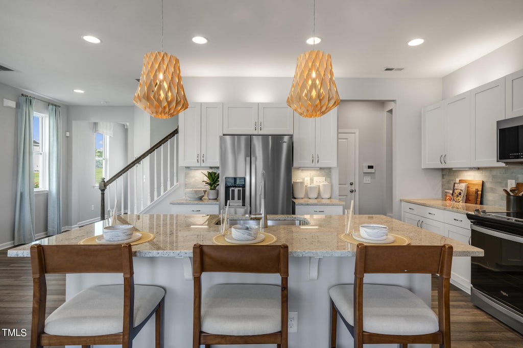 kitchen featuring an island with sink, stainless steel appliances, and dark hardwood / wood-style flooring