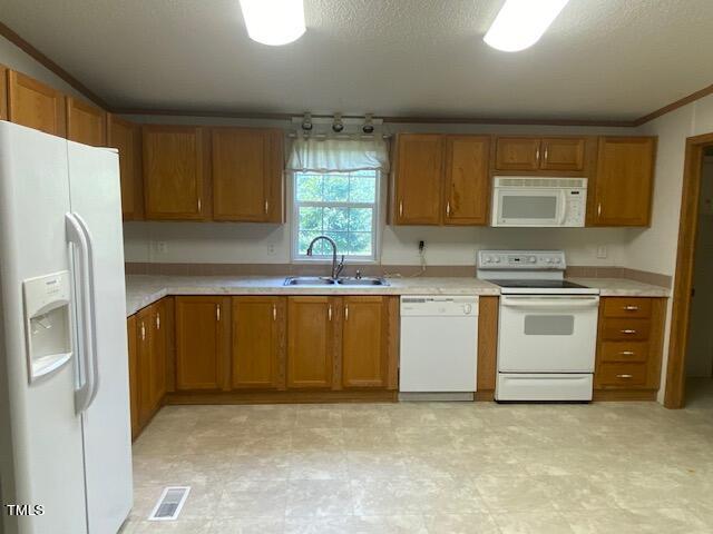 kitchen featuring ornamental molding, white appliances, sink, and a textured ceiling