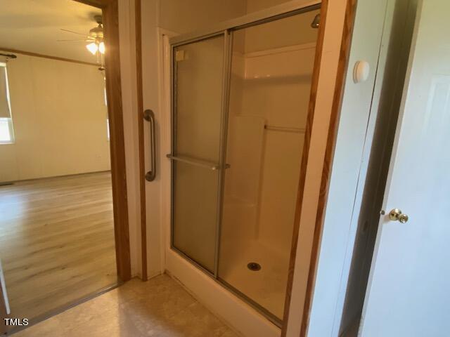 bathroom with a shower with door, ceiling fan, and hardwood / wood-style floors