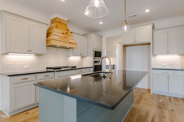 kitchen featuring dark countertops, custom range hood, appliances with stainless steel finishes, and a sink