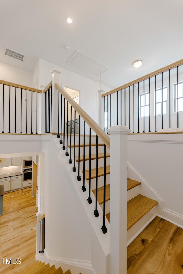 stairs with wood finished floors, visible vents, baseboards, attic access, and recessed lighting